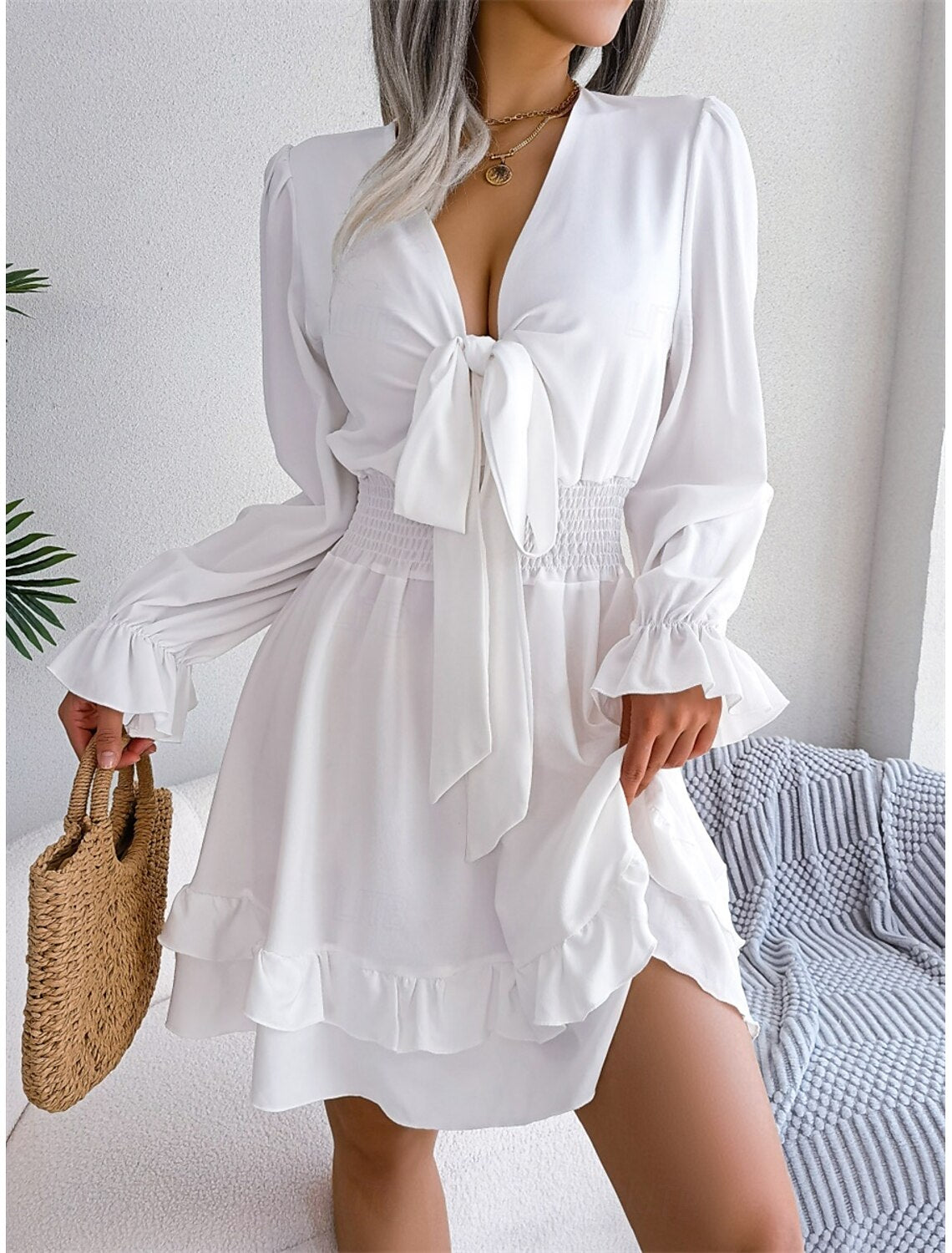 Woman wearing an elegant white V-neck long sleeve A-line mini dress.