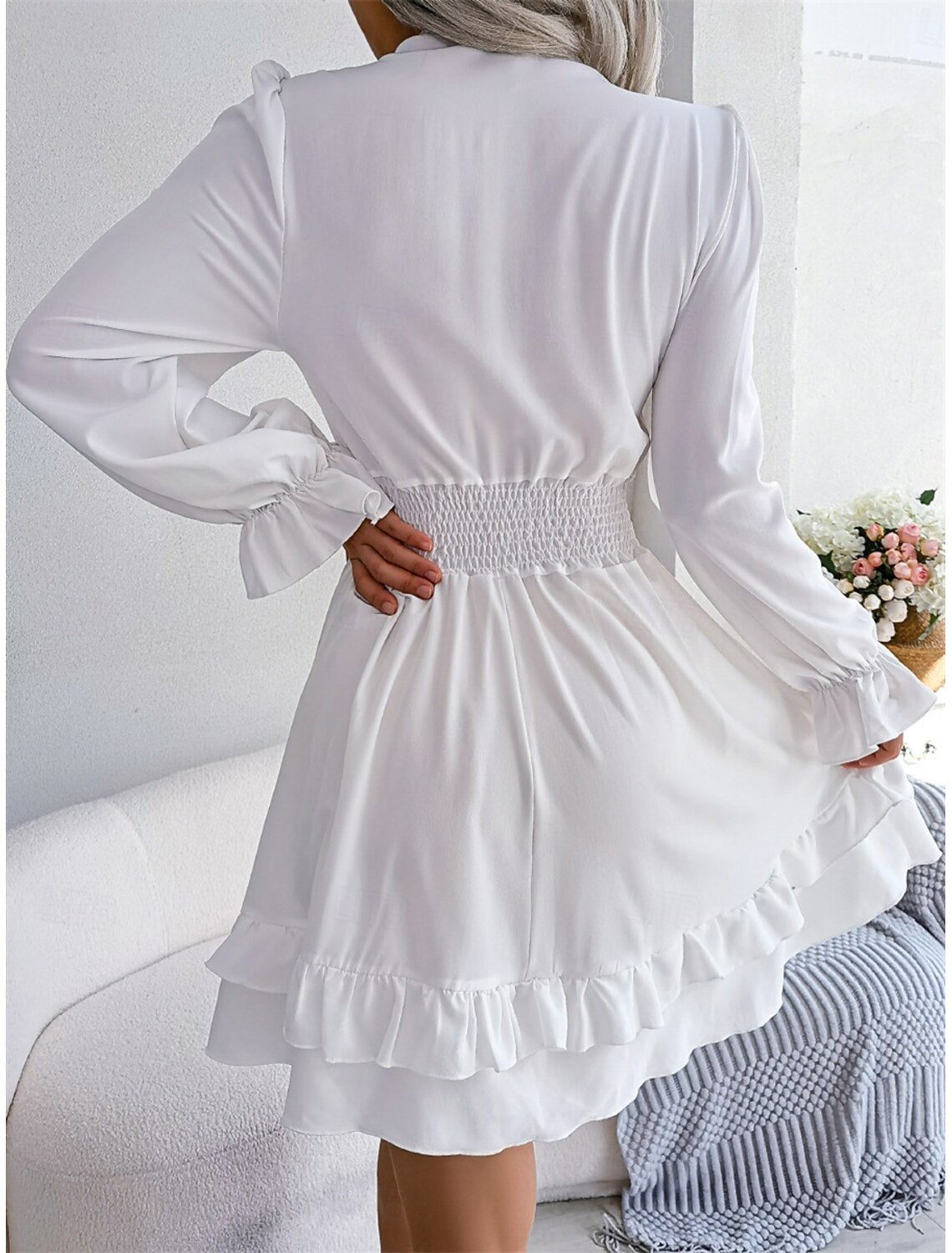 Close-up of the fabric and V-neck detail on the white A-line mini dress.