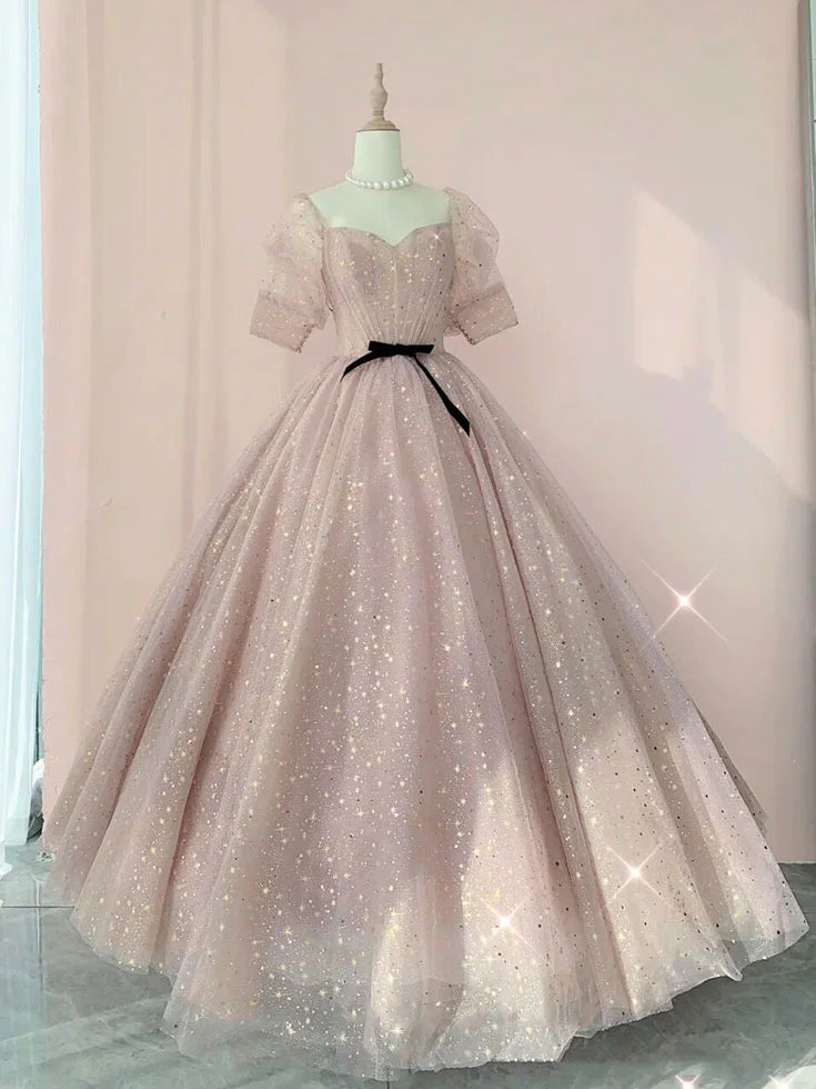 Model wearing a champagne tulle long prom dress with a cinched waist.