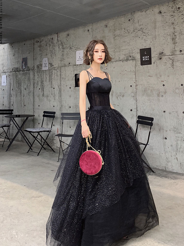 Woman wearing a black sequin tulle long prom dress with spaghetti straps.