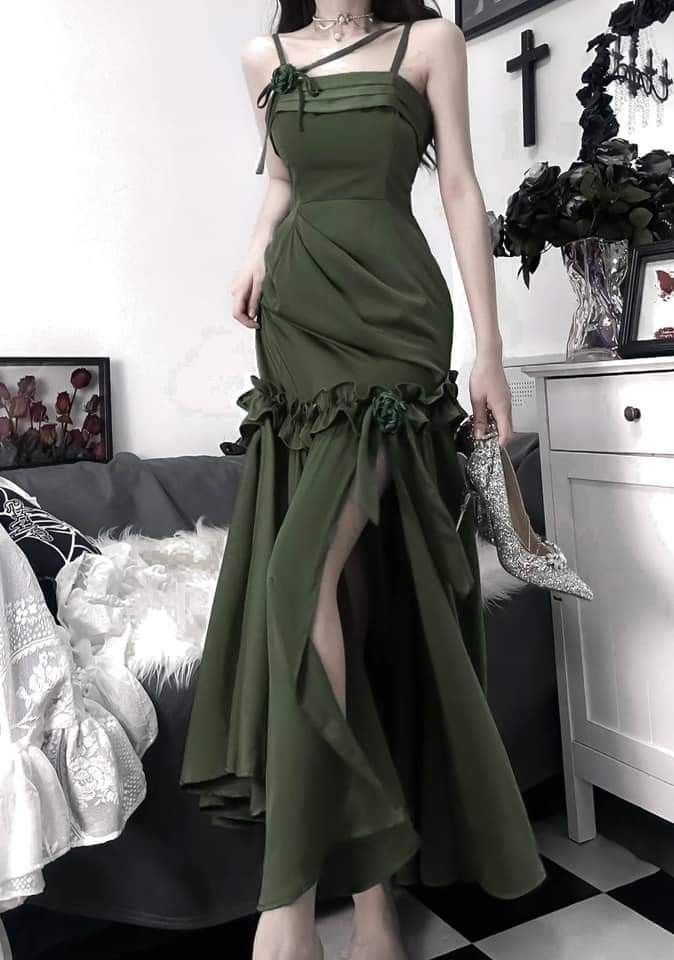 Model in dark green satin mermaid prom dress with spaghetti straps, ruffles, and a large back bow.