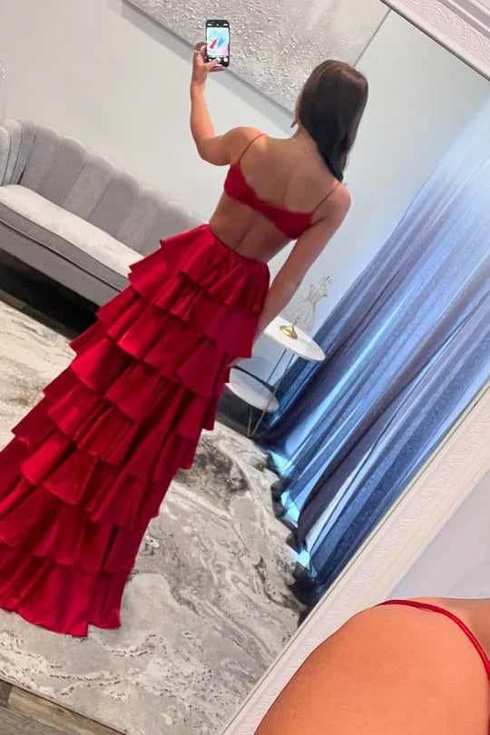 Back view of a woman in a flowing layered satin prom dress with spaghetti straps.