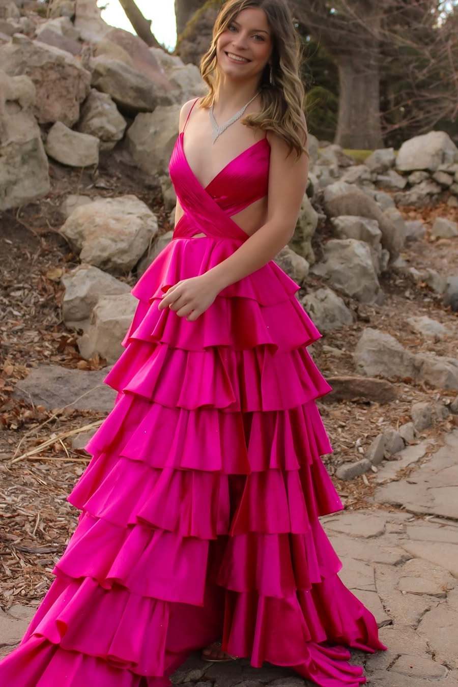 Side profile of a woman in a glamorous satin prom dress with a high leg slit.