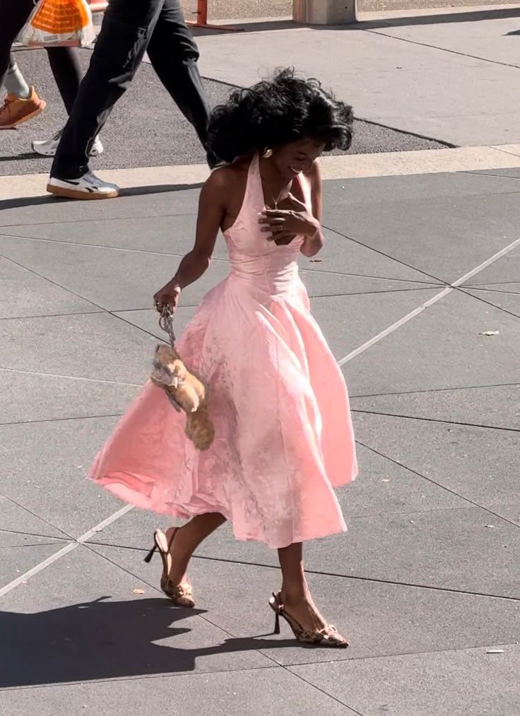 Woman wearing a pink printed halter neck evening gown with a cinched waist.