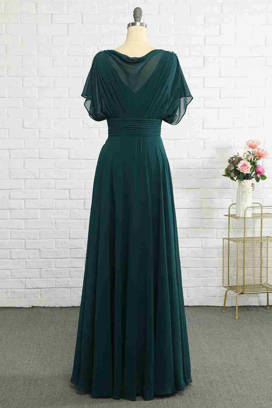 Side view of a hunter green chiffon dress, highlighting the banded waist and flowing skirt.
