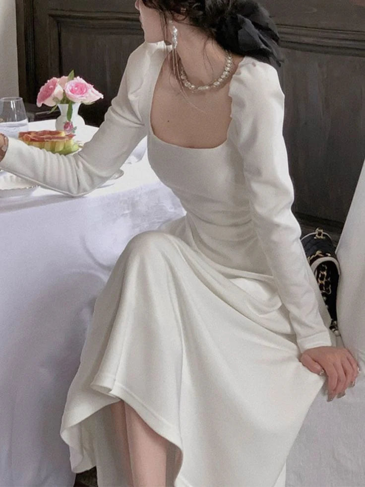 Model wearing a dark long-sleeve A-line evening dress, standing gracefully.