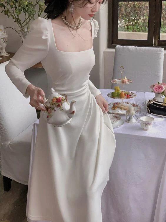 Side view of a model in a dark long-sleeve A-line evening dress, showcasing the silhouette.