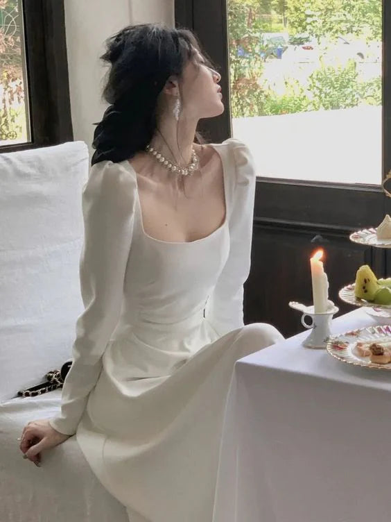 Close-up of the bodice and long sleeves of a dark A-line evening dress on a model.