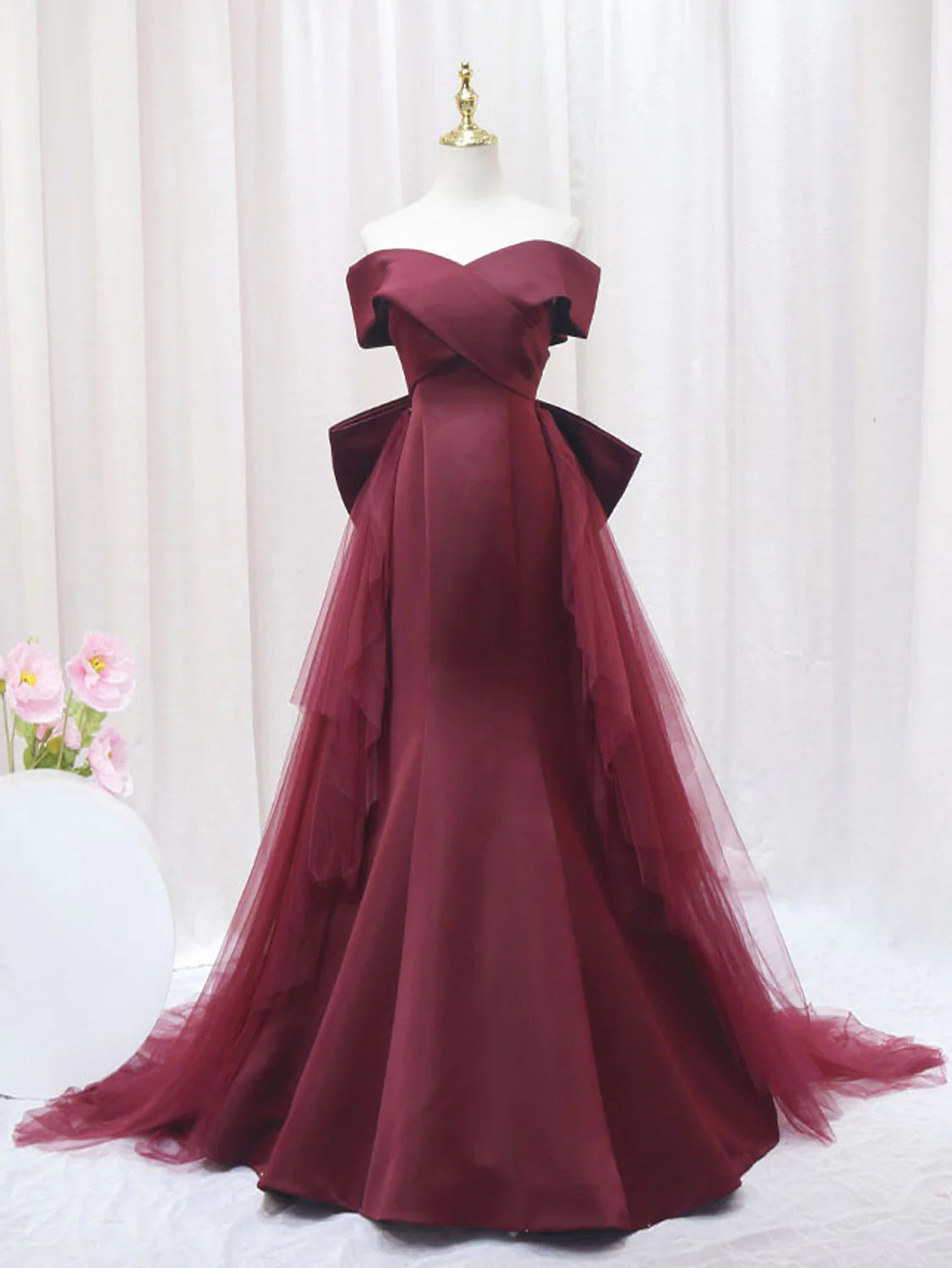 Woman wearing a long burgundy mermaid tulle prom dress, front view.