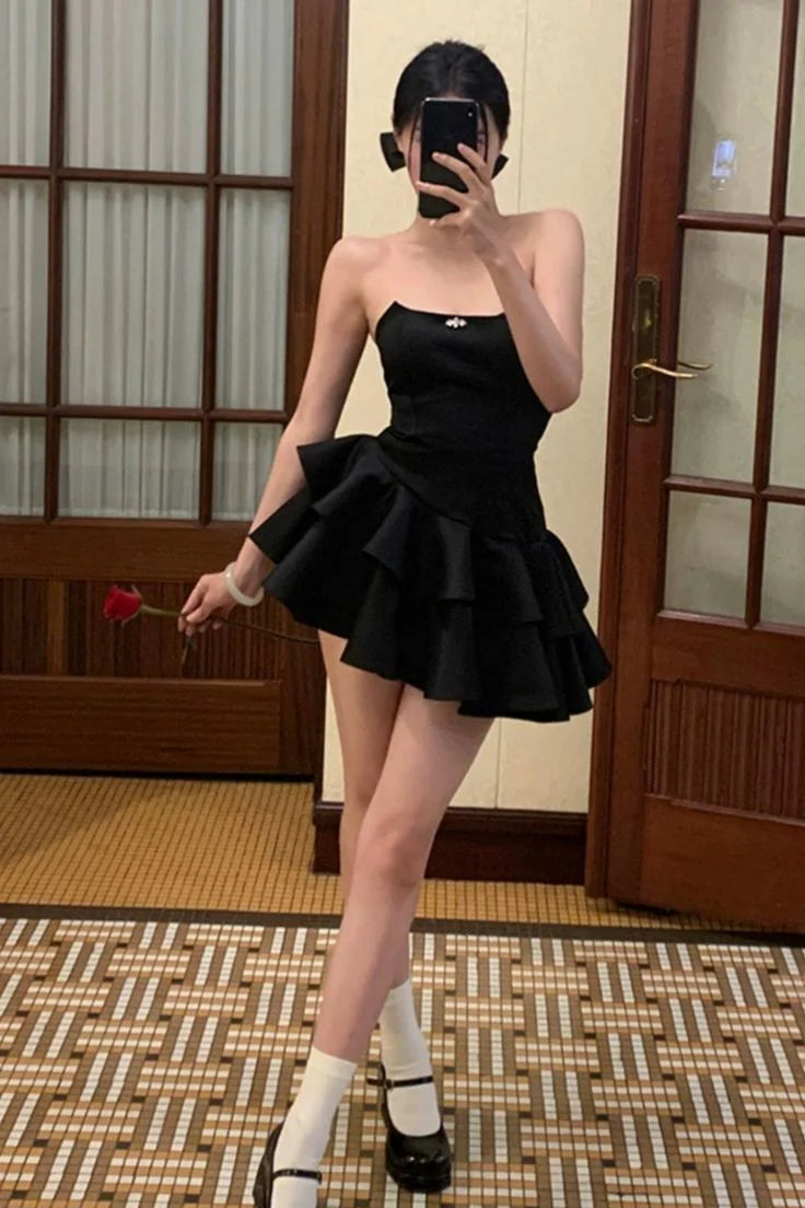Woman posing in a black strapless A-line short satin prom dress.