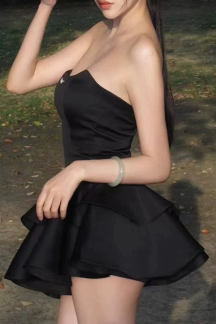 Back view of a woman wearing a black strapless satin cocktail dress.