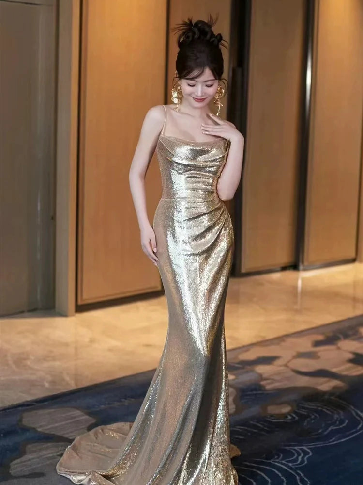 Front view of a woman wearing a sparkling gold sequin mermaid evening dress with a high neck.