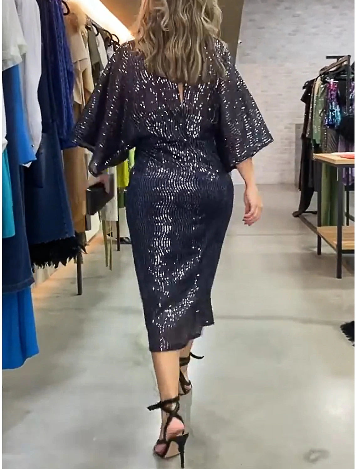Elegant woman posing in a glittery V-neck 3/4 sleeve sequin dress.