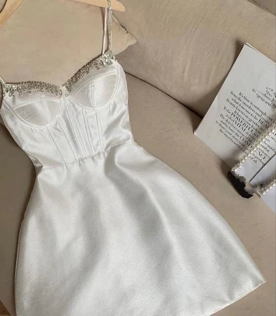 Model wearing a white A-line short homecoming dress with spaghetti straps and intricate beading.