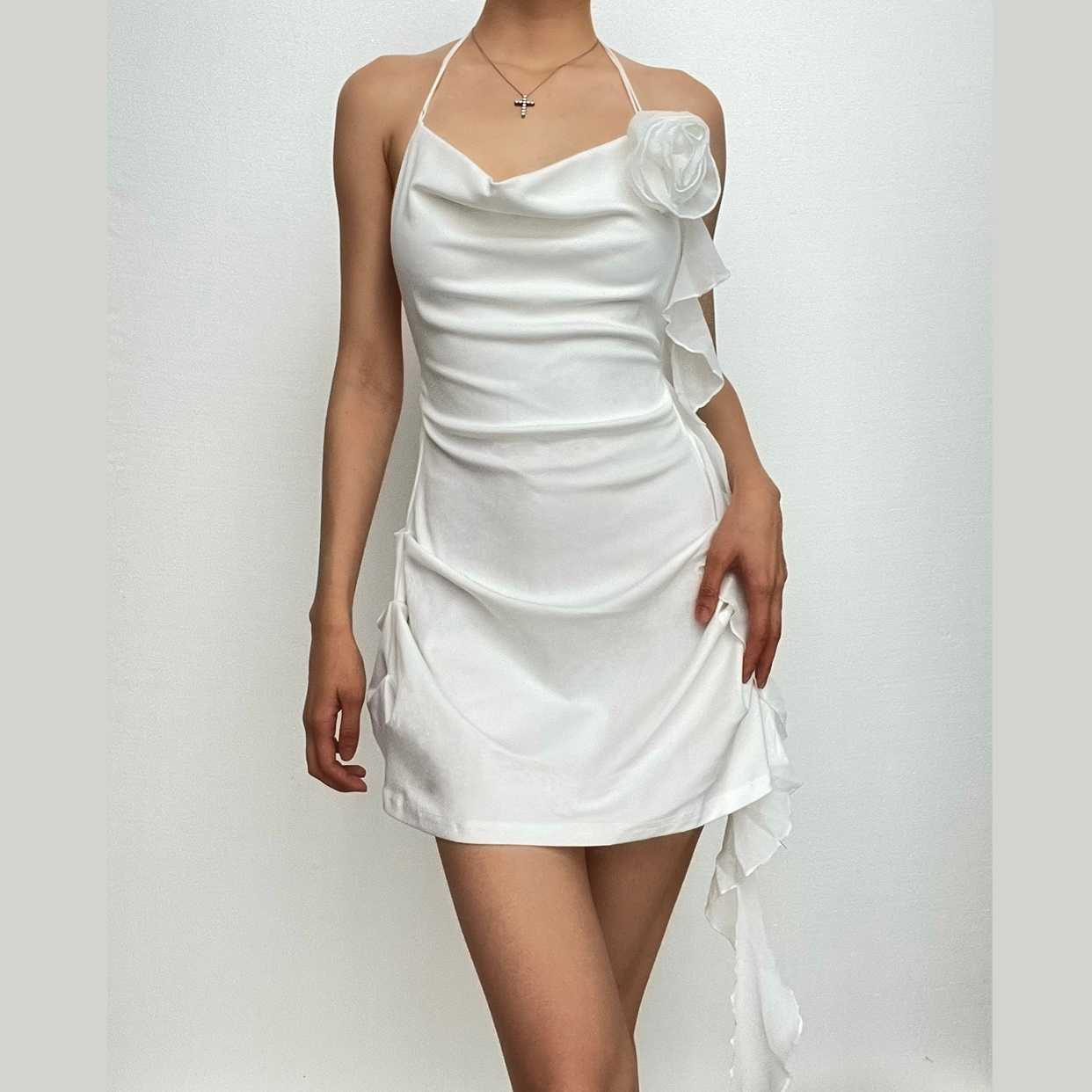 Model wearing a white halter cowl neck ruched mini homecoming dress with floral applique, front view.